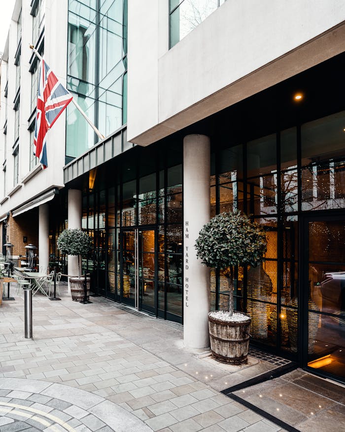 Exterior of a modern hotel in London with a British flag displayed and sleek glass design.